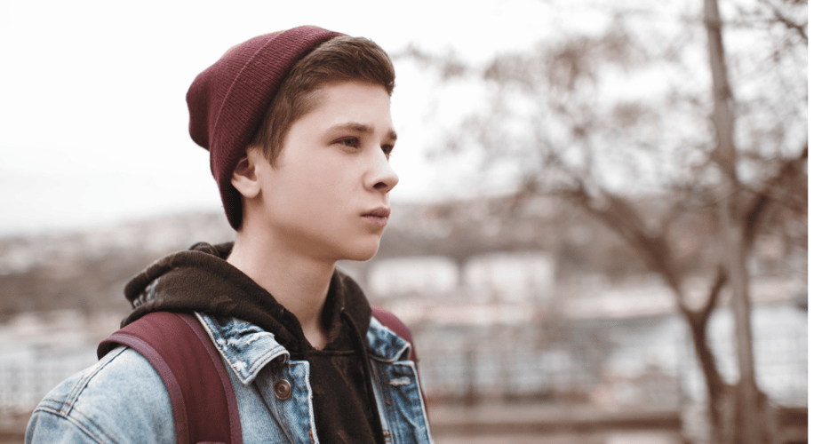 young man walking outside with backpack